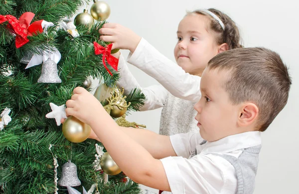 Děti zdobí vánoční strom s míčky. — Stock fotografie