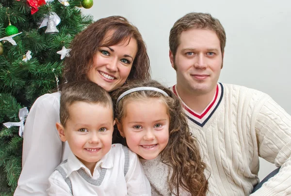 Happy family members sitting over christmas tree — Stock Photo, Image