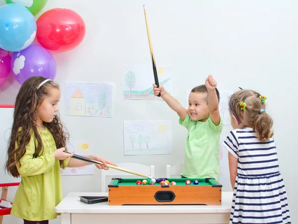 Дети играют в мини-бильярд в игровой комнате — стоковое фото