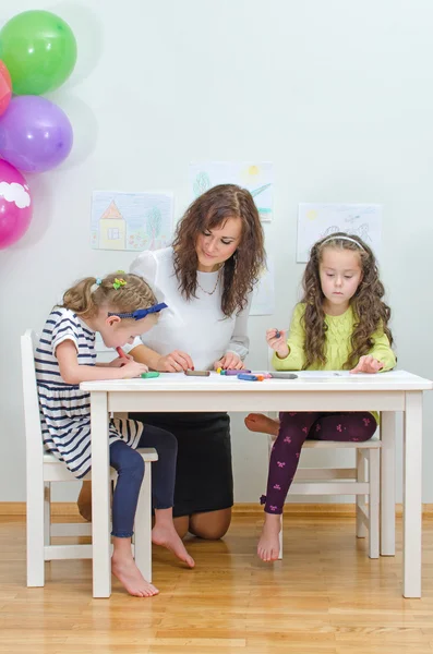 Leraar met twee meisjes in de kleuterschool. — Stockfoto