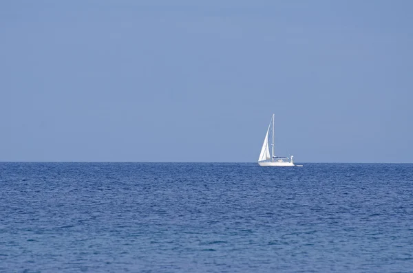 Мирный океанский пейзаж с белой яхтой вдали — стоковое фото
