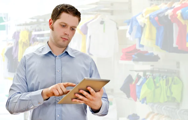 Toezichthouder met de tablet pc in de kledingwinkel — Stockfoto