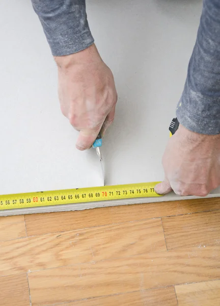 Manos masculinas que miden y cortan placas de yeso — Foto de Stock