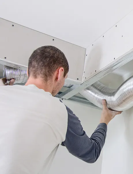 Homem a montar o sistema de ventilação dentro de casa — Fotografia de Stock