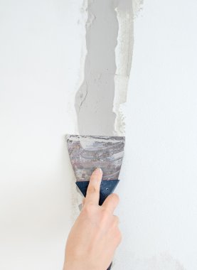 Female hand repairs wall with spackling paste clipart