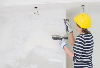 kadın sıvacı, duvar spackling yapıştır ile onarır. alan metni.