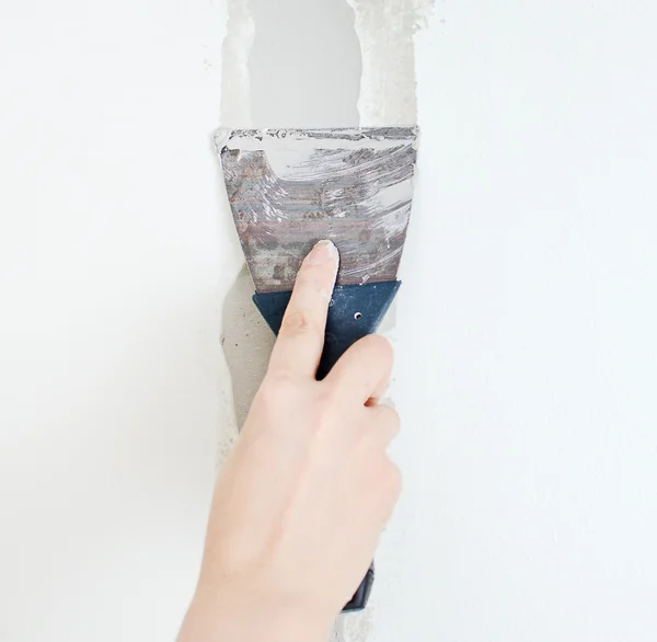 Female hand repairs wall with spackling paste — Stock Photo, Image