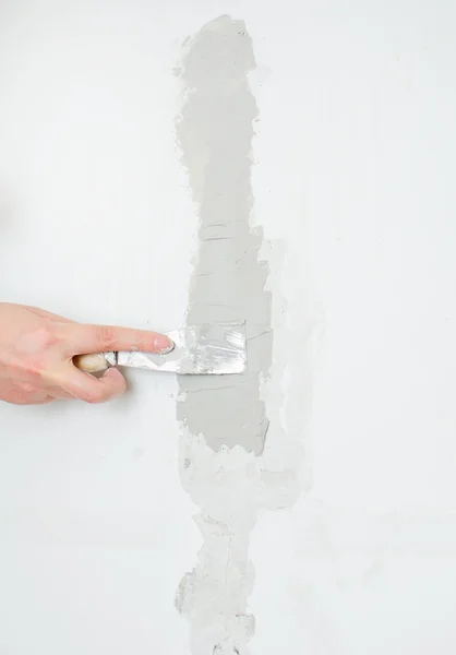 Vrouwelijke hand reparaties muur met spackling plakken — Stockfoto