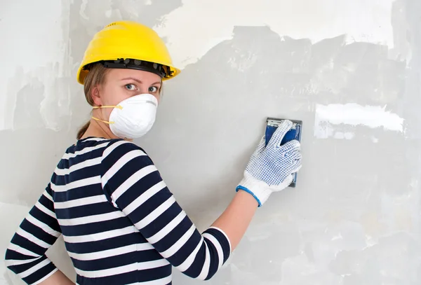 Yesero femenino en sombrero duro puliendo la pared . — Foto de Stock