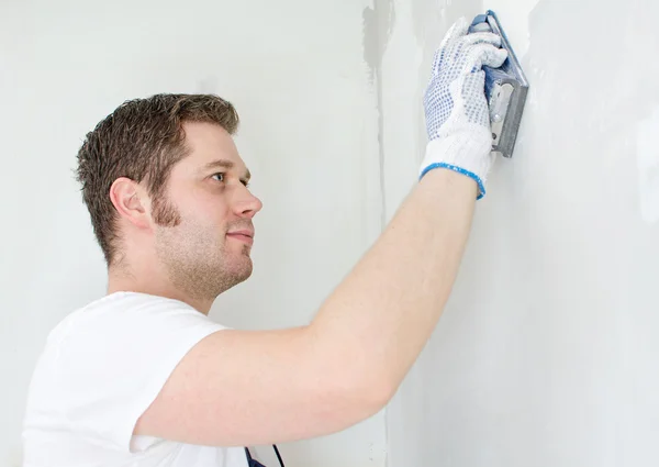 Male plasterer in uniform polishing the wall. — Stock Photo, Image