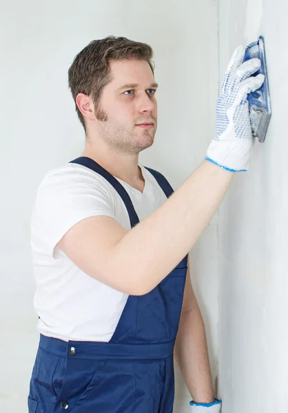 Estucador masculino no polimento uniforme da parede . — Fotografia de Stock