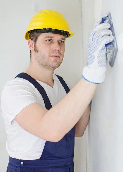 Yesero masculino en sombrero duro puliendo la pared . — Foto de Stock