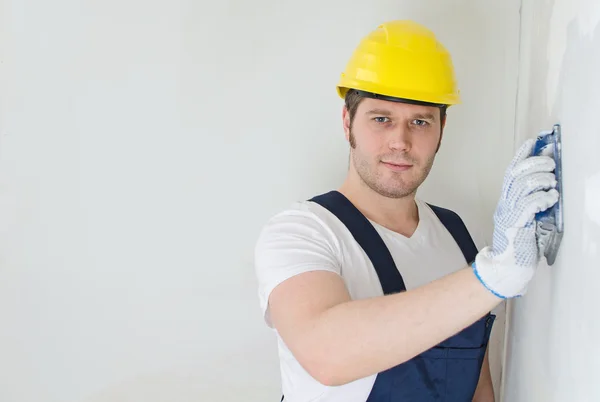 Yeso masculino en sombrero duro puliendo la pared. Espacio para texto . — Foto de Stock