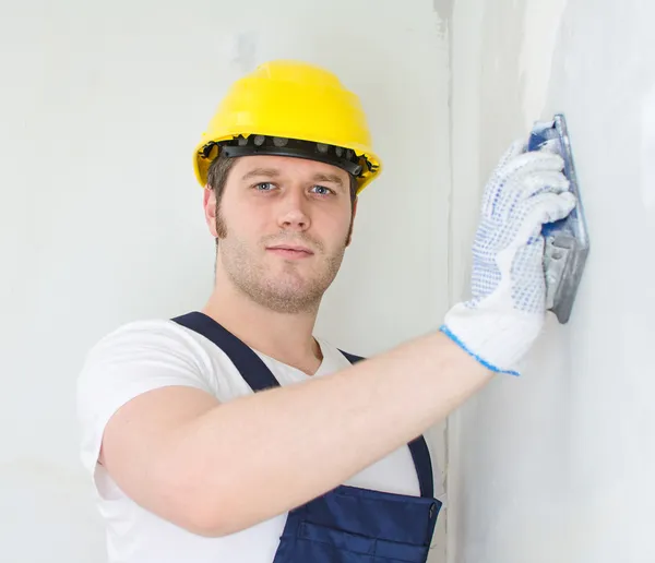 Mannelijke Stukadoor in harde hoed polijsten van de muur. — Stockfoto