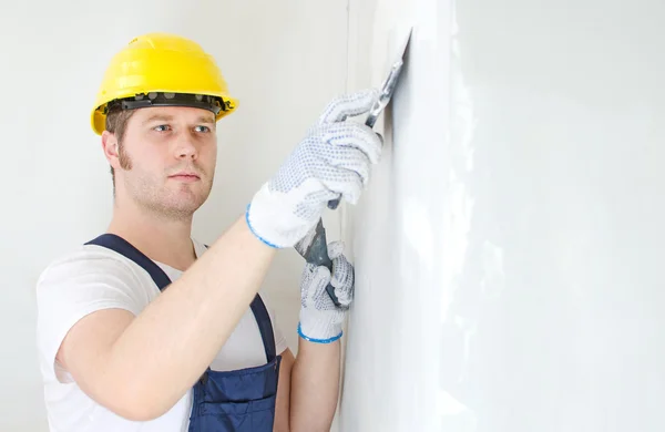 Mannelijke bouwer reparaties muur met spackling pasta — Stockfoto