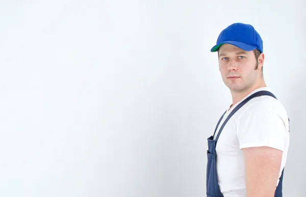 Tradesman in uniform standing near the wall. Space for your text. — Stock Photo, Image
