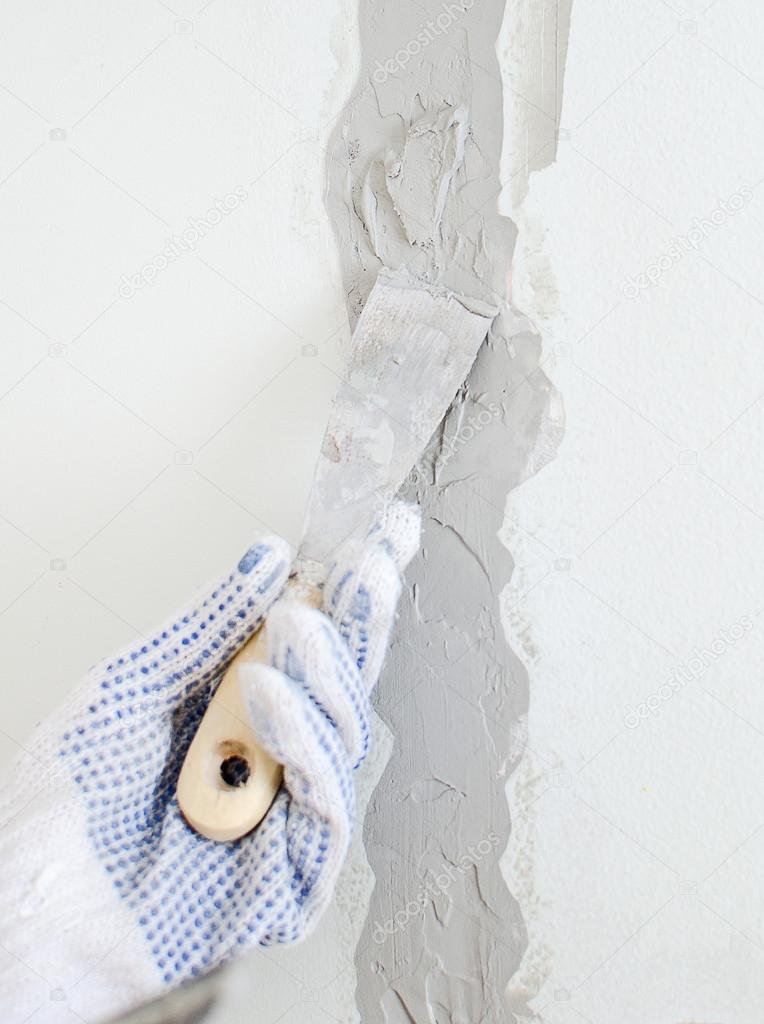 Female hand repairs wall with spackling paste