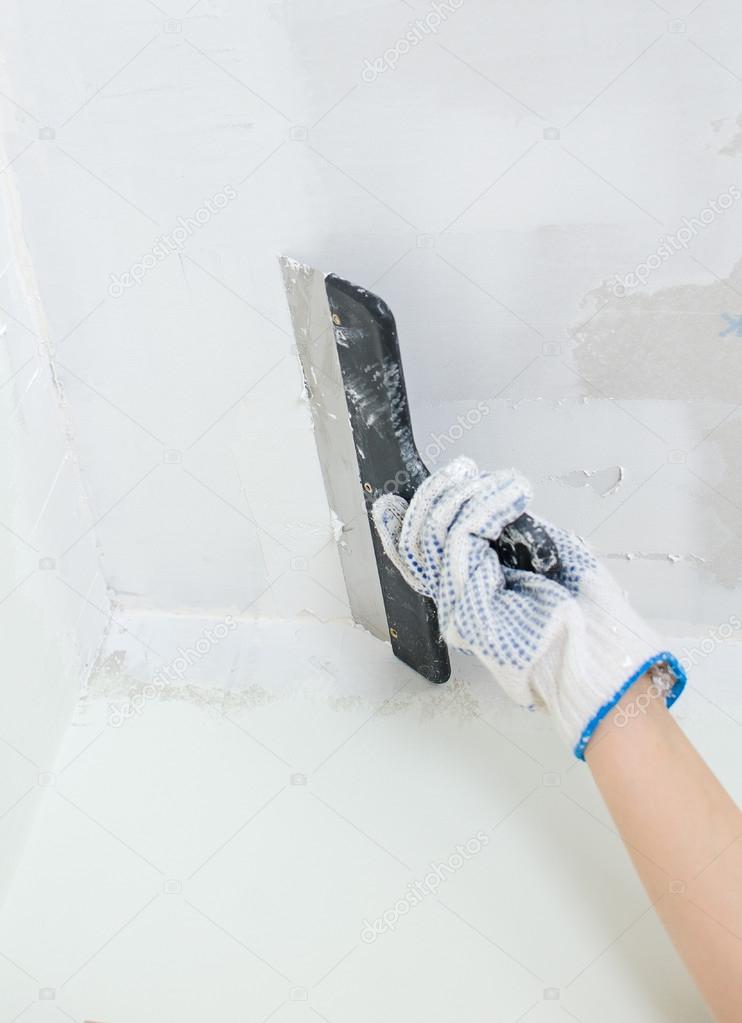 Hand repairs gypsum plasterboard frame with spackling paste