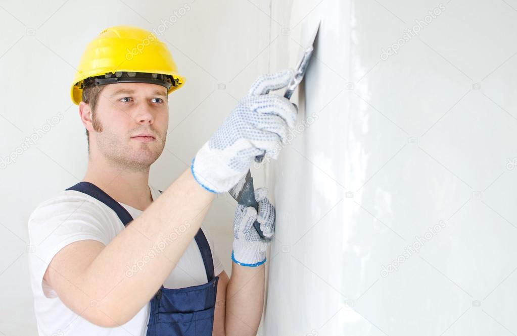 Male builder repairs wall with spackling paste
