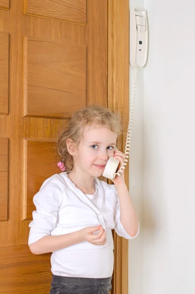 Lilla flickan talar på porttelefonen hemma. — Stockfoto