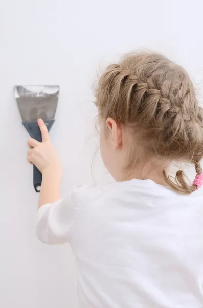 Little girl repairs wall with spackling paste. — Stock Photo, Image