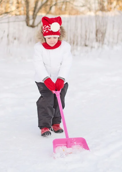 Söt liten flicka skotta snö. — Stockfoto