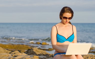 plajda çalışan dizüstü bilgisayar ile bir kadın. metin için yer.