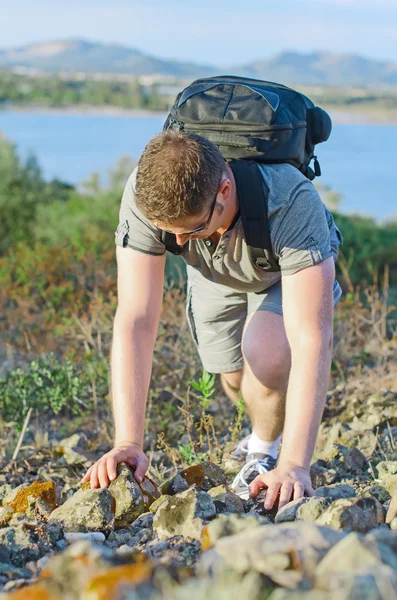 Αρσενικό τουρίστας με το σακίδιο ανεβαίνει ένα βουνό. — Φωτογραφία Αρχείου