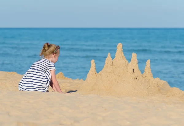 Bambina con castello di sabbia sulla spiaggia . — Foto Stock