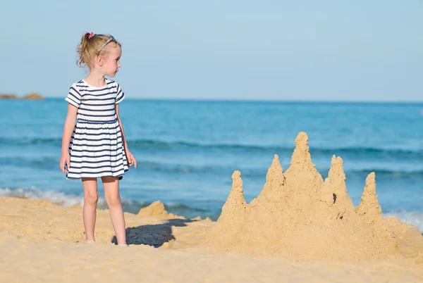 Bambina con castello di sabbia sulla spiaggia . — Foto Stock