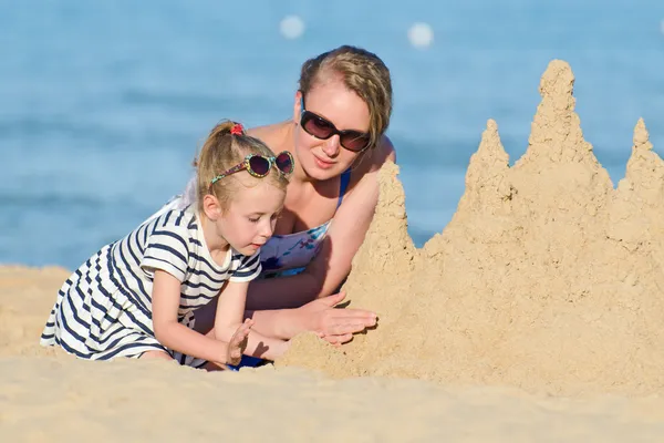Familj med sandslott på stranden. — Stockfoto