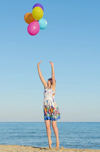 Молодая женщина с красочными воздушными шарами над морем . — стоковое фото