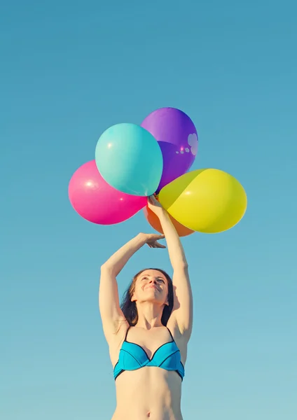女人试着抓住五颜六色的气球 — 图库照片