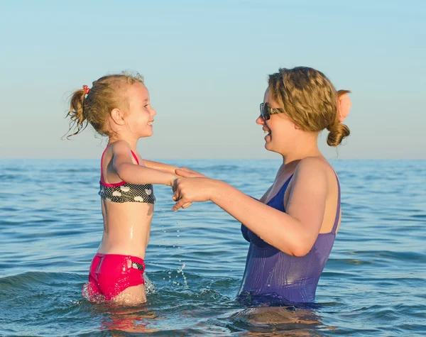 Frau bringt Kind Schwimmen im Meer bei. — Stockfoto