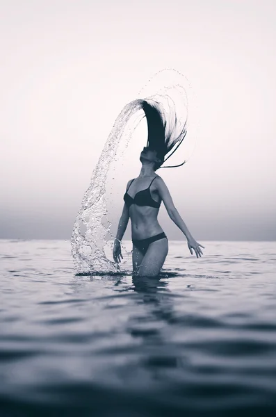 Femme dans l'eau agitant les cheveux. Effet noir et blanc . — Photo