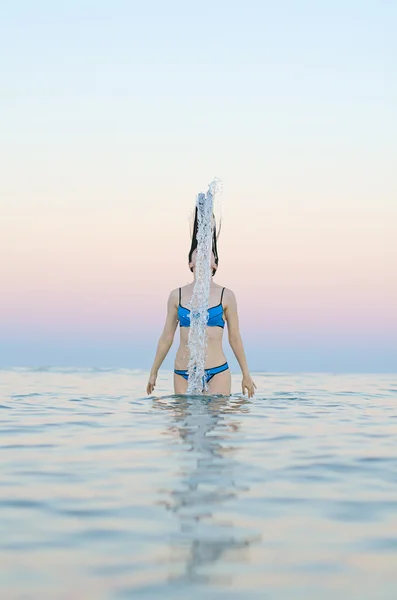Frau im Wasser wedelt mit Haaren. — Stockfoto