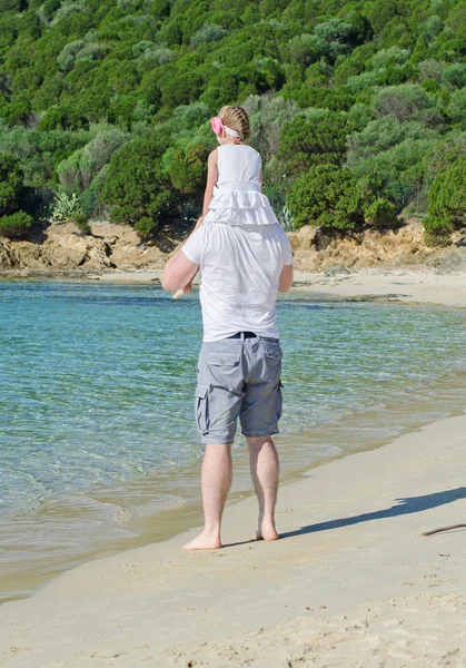 Homem com filha nos ombros em pé na praia . — Fotografia de Stock