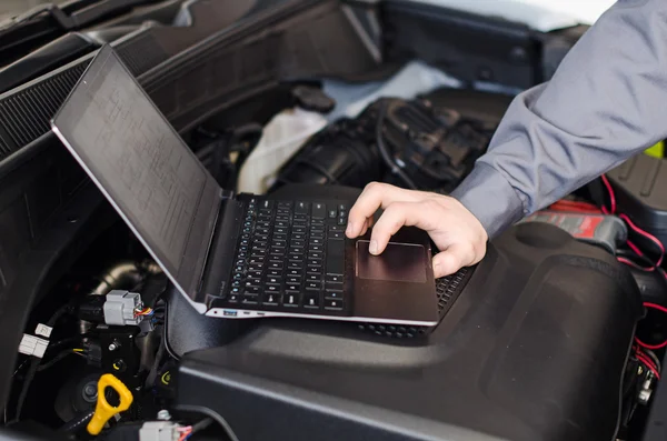 Mechanic with laptop diagnoses car in workshop. — Stock Photo, Image