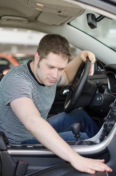 Homem examinando carro novo na concessionária . — Fotografia de Stock