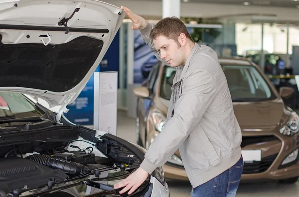 Mann begutachtet Neuwagen im Autohaus. — Stockfoto