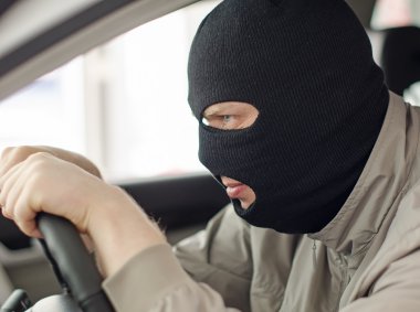 Thief in mask steals expensive new car. clipart
