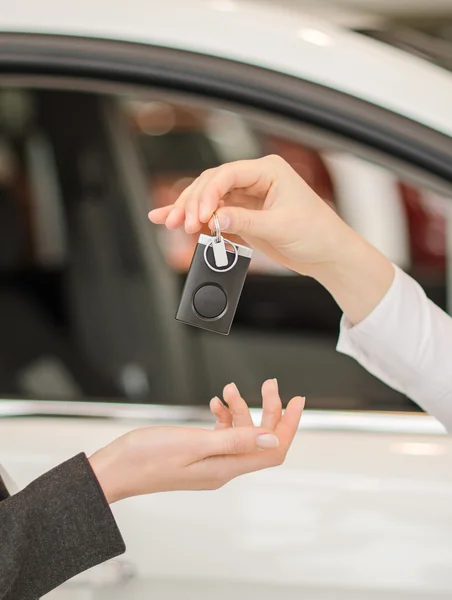 Жіноча рука отримує сучасний ключ автомобіля на автомобільному фоні — стокове фото