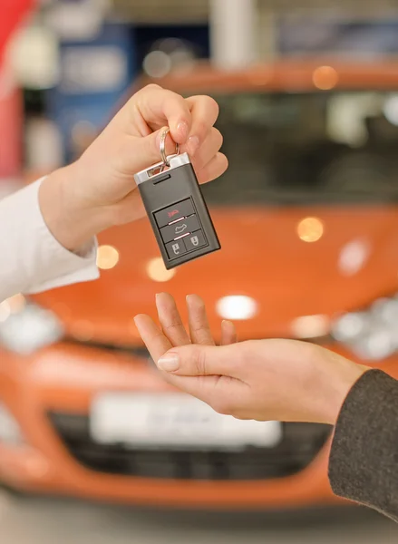 Female hand getting modern car key on a car background — Stock Photo, Image