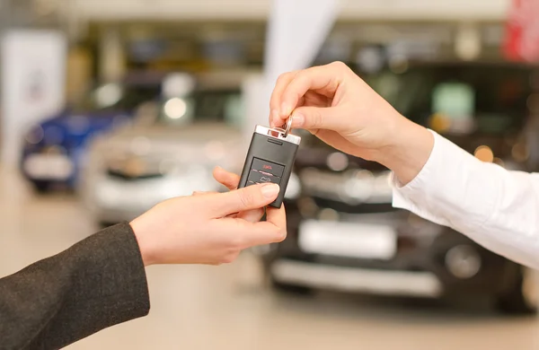 Weibliche Hand bekommt modernen Autoschlüssel auf mehreren Autohintergründen — Stockfoto