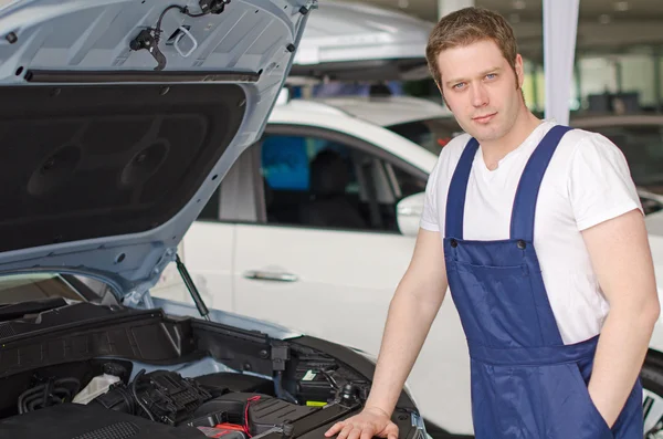 Joven mecánico guapo de pie cerca de la campana del coche abierto — Foto de Stock