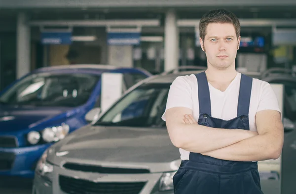 Joven mecánico guapo en la concesionaria de automóviles. Lugar para el texto . — Foto de Stock