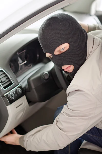 Thief in mask steals expensive new car. — Stock Photo, Image