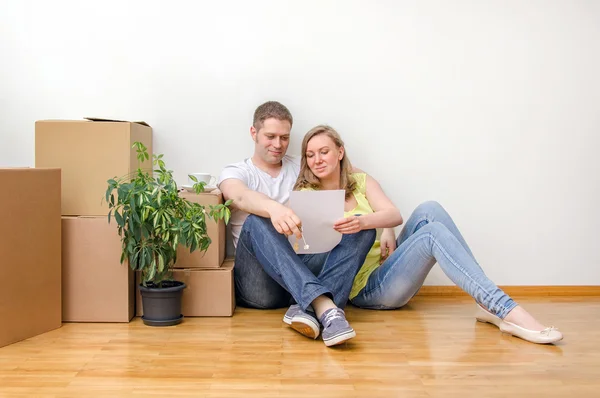 Neues Heimkonzept. Glückliche Familie sitzt in der Nähe von Kisten. — Stockfoto