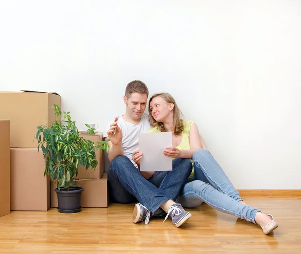 Novo conceito de casa. Família feliz sentado perto de caixas . — Fotografia de Stock