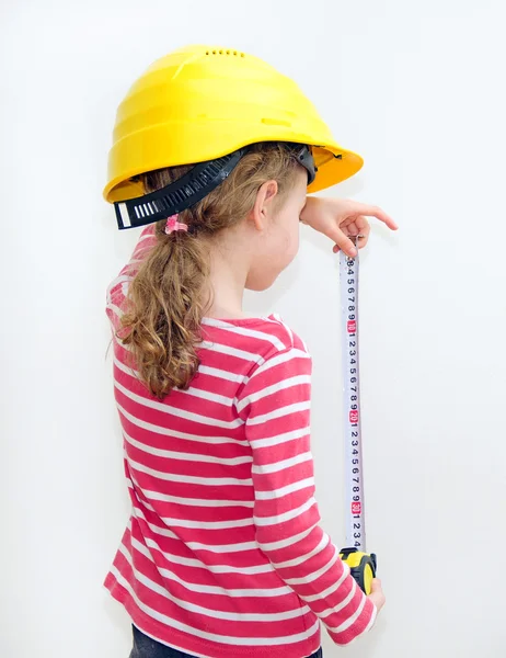 Duvar şerit metre ile ölçme baret, küçük kız. — Stok fotoğraf